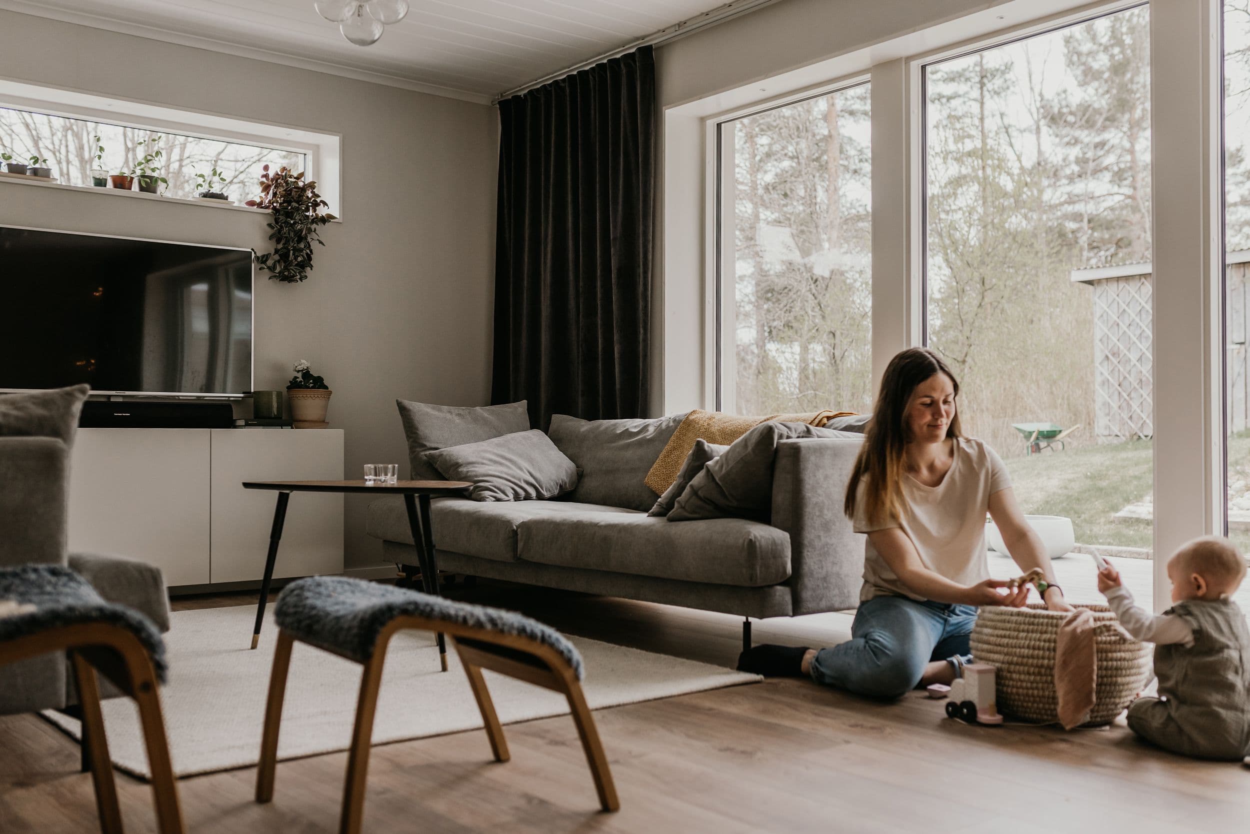 Mamma i vardagsrum som sitter och leker med sitt barn på golvet